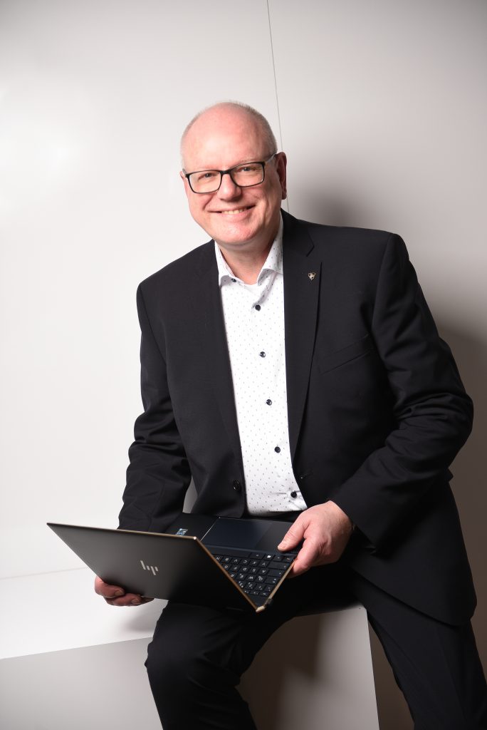 Ralf Droste sitzt mit aufgeklapptem Laptop auf dem Oberschenkel und arbeitet konzentriert – persönlicher, praxisnaher Excel-Trainer.